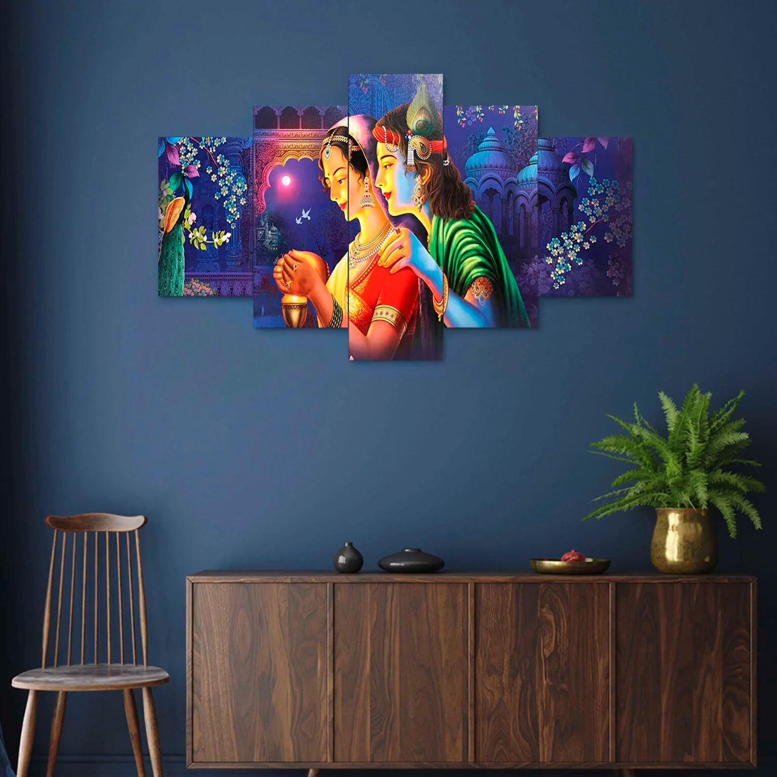 Decor Home Craft A Decor Home Radha Krishna Wall Painting display featuring vibrant, colorful illustrations of Hindu deities in a traditional style, set against a dark blue wall above a wooden cabinet with a plant and décor, ideal for enhancing the ambiance of an office or living room.